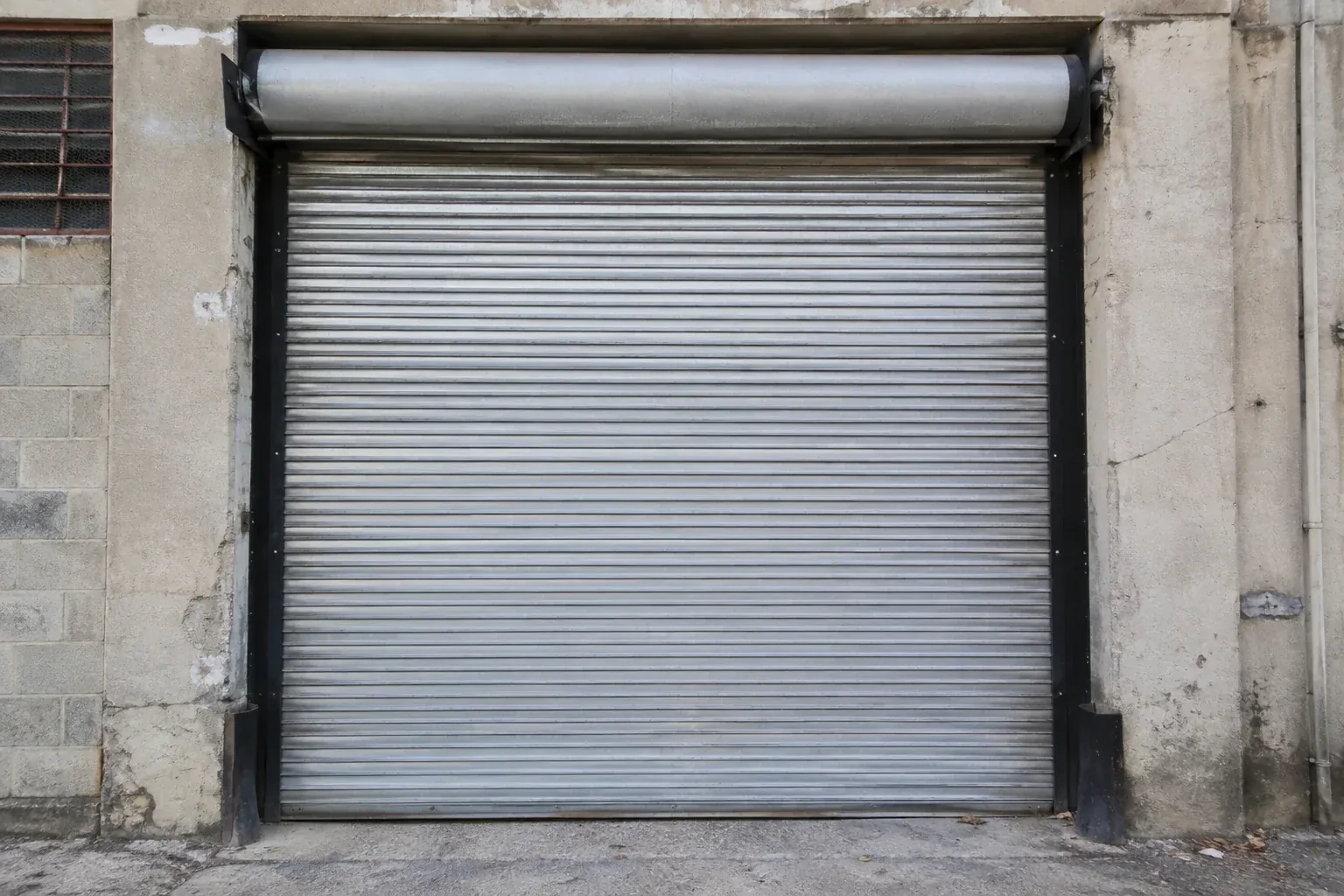 Closed metal rolling shutter in a weathered warehouse opening. — Commercial Rolling Door Repair, Maple