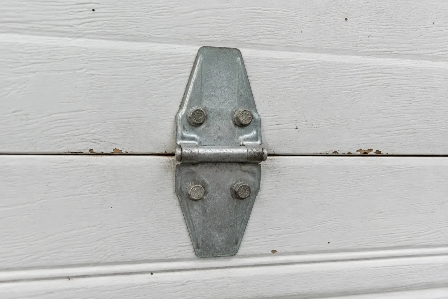 Metal center hinge across a seam in a white sectional garage door. — Garage Door Hinge Replacement, Vaughan